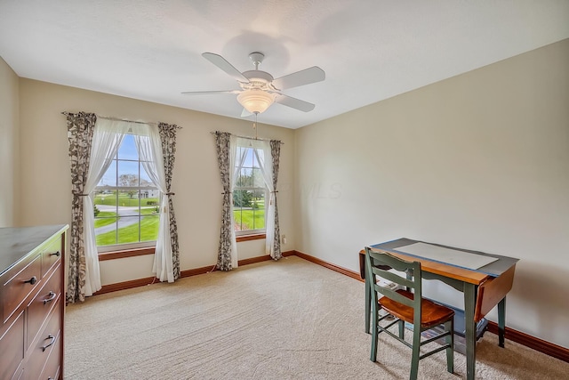 dining area with a ceiling fan, baseboards, and light colored carpet