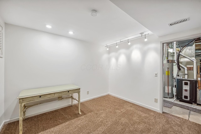 basement featuring visible vents, baseboards, water heater, and carpet