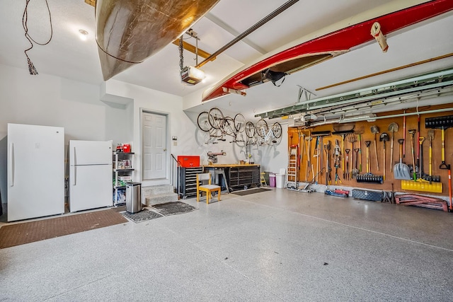 garage with freestanding refrigerator, a workshop area, and a garage door opener