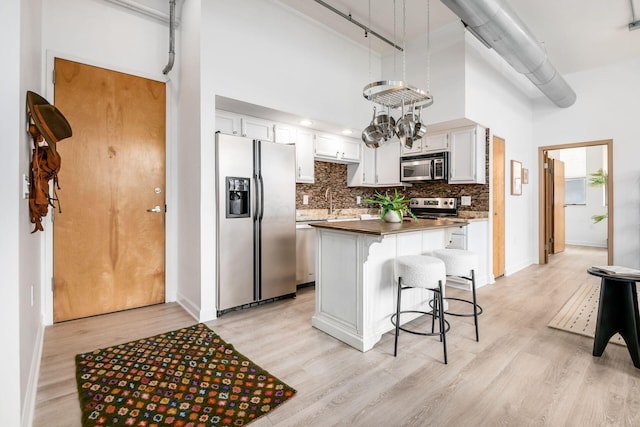 kitchen with dark countertops, stainless steel appliances, a kitchen island, and white cabinets