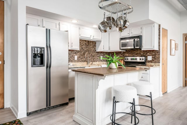 kitchen featuring white cabinetry, stainless steel appliances, a breakfast bar area, and a center island