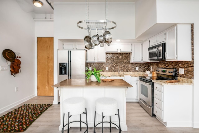 kitchen featuring light wood-type flooring, white cabinetry, appliances with stainless steel finishes, and tasteful backsplash