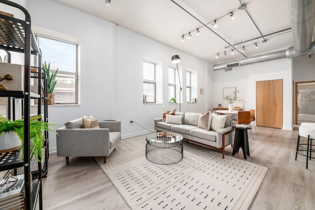 living room featuring light wood-style floors, track lighting, baseboards, and a wealth of natural light