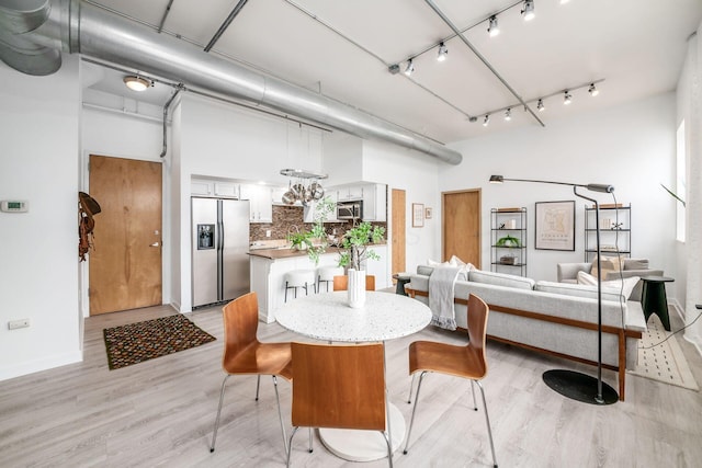 dining area with light wood-type flooring and track lighting