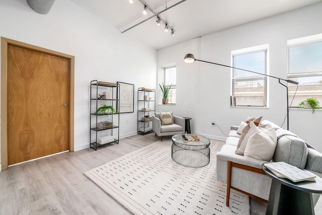 living area featuring light wood-type flooring, rail lighting, and baseboards