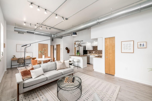 living area featuring light wood-style flooring, track lighting, visible vents, and baseboards