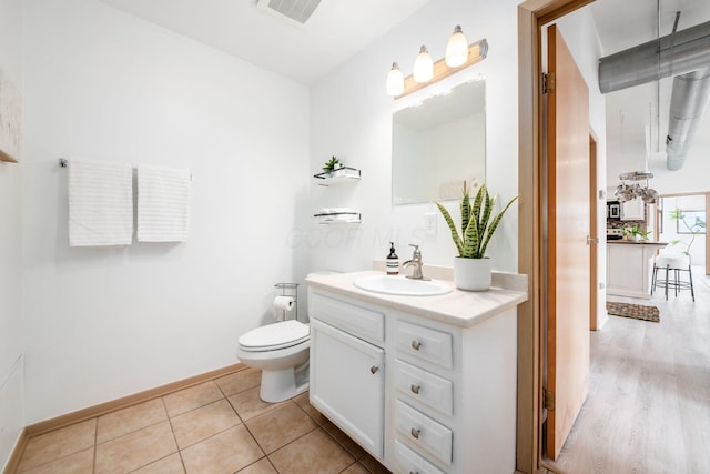 bathroom featuring tile patterned flooring, toilet, vanity, visible vents, and baseboards