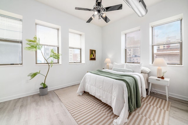 bedroom featuring ceiling fan, light wood-type flooring, and baseboards