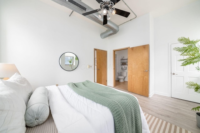 bedroom featuring visible vents, a high ceiling, connected bathroom, and light wood-style flooring