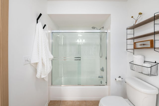 full bathroom featuring combined bath / shower with glass door, toilet, and tile patterned floors