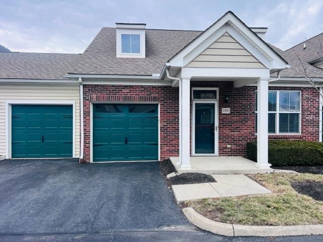 view of front of home featuring a garage, a shingled roof, aphalt driveway, and brick siding