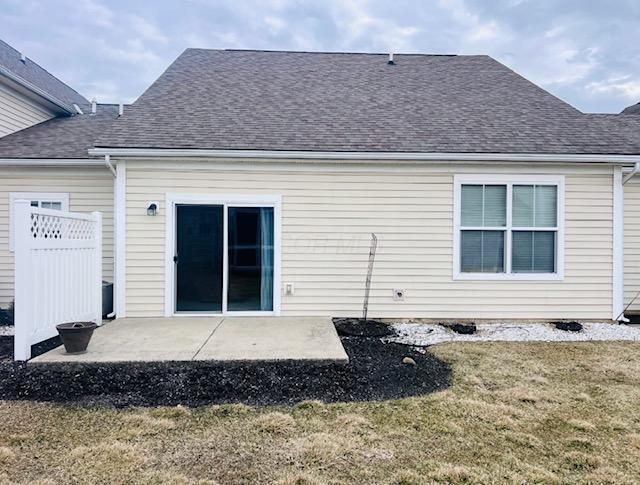 back of property featuring roof with shingles, a yard, fence, and a patio