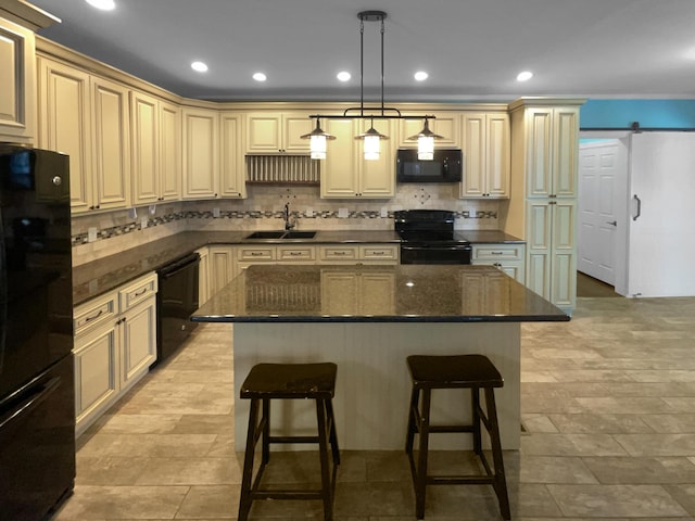 kitchen featuring a barn door, a kitchen island, hanging light fixtures, black appliances, and a sink