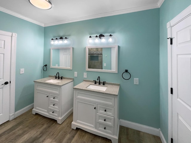 bathroom with ornamental molding, two vanities, a sink, and wood finished floors