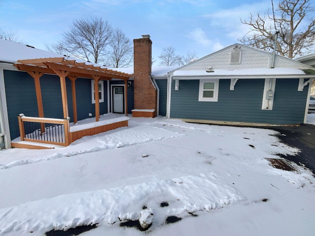 snow covered house featuring a chimney, a porch, and a pergola