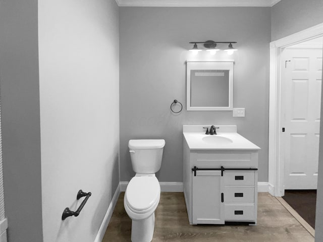 bathroom featuring baseboards, vanity, toilet, and wood finished floors