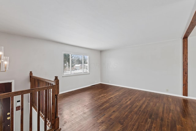 empty room featuring baseboards and dark wood-style flooring