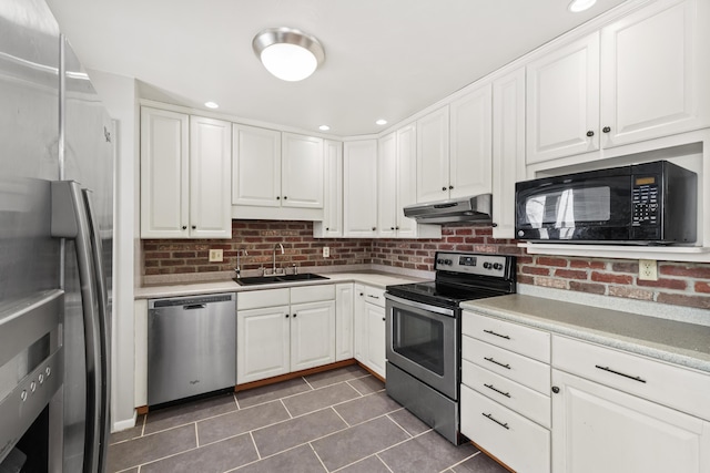 kitchen with stainless steel appliances, light countertops, white cabinets, a sink, and under cabinet range hood