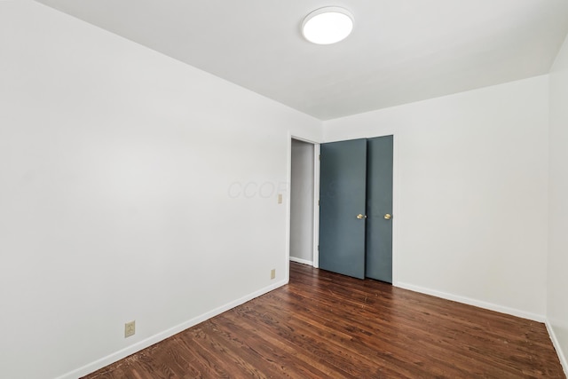 spare room featuring dark wood finished floors and baseboards