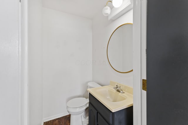 half bathroom featuring vanity, toilet, and wood finished floors