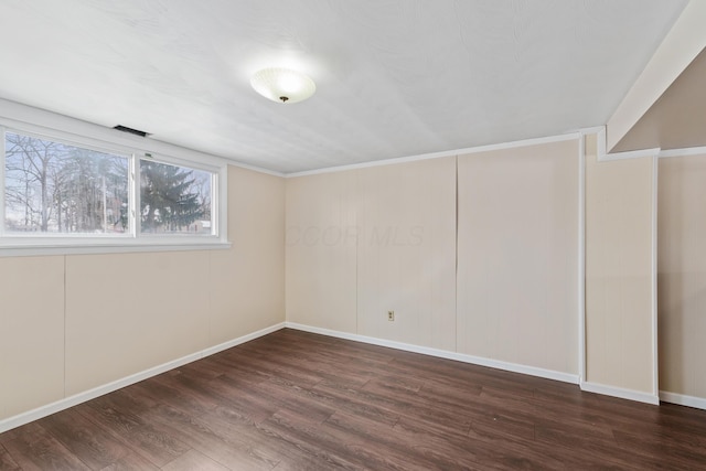 unfurnished room featuring dark wood-style floors, visible vents, and baseboards