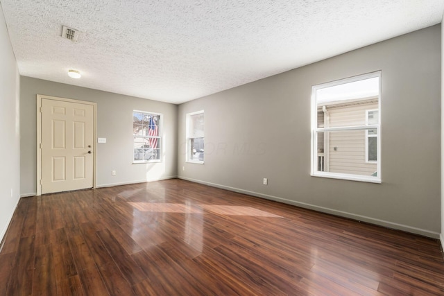 unfurnished room with a textured ceiling, dark wood-type flooring, and baseboards