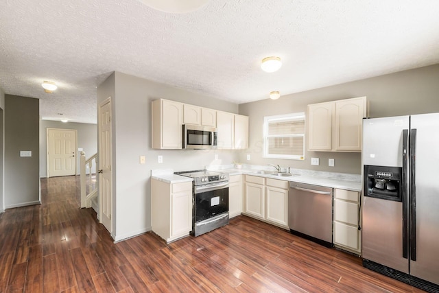 kitchen featuring stainless steel appliances, light countertops, dark wood finished floors, and a textured ceiling