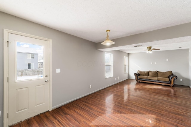 living area featuring a textured ceiling, ceiling fan, dark wood-style flooring, visible vents, and baseboards