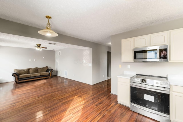 kitchen featuring white cabinets, dark wood finished floors, appliances with stainless steel finishes, open floor plan, and light countertops