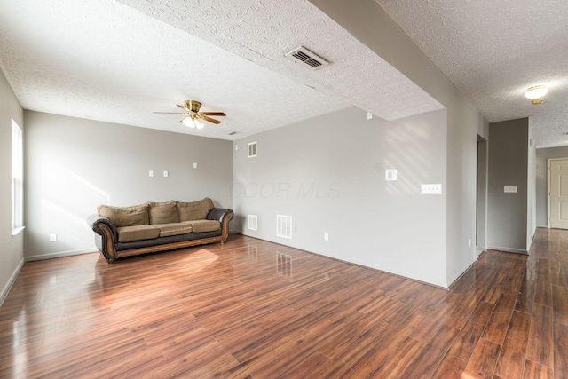 living room featuring ceiling fan, a textured ceiling, visible vents, and dark wood-style flooring