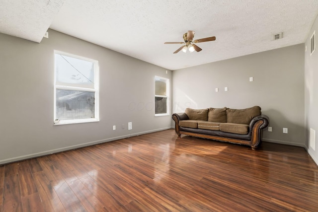 living room with dark wood-style flooring, visible vents, a ceiling fan, a textured ceiling, and baseboards