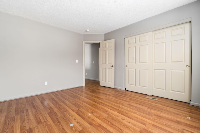 unfurnished bedroom with a textured ceiling, light wood-type flooring, and baseboards