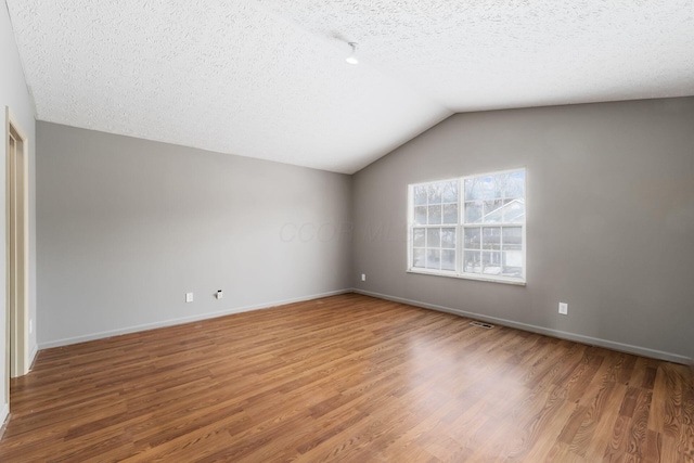 bonus room featuring a textured ceiling, visible vents, vaulted ceiling, and wood finished floors