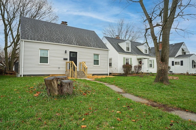 view of front of house featuring a shingled roof, a chimney, and a front yard