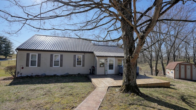 view of front of house featuring metal roof, an outbuilding, a storage shed, and a front yard