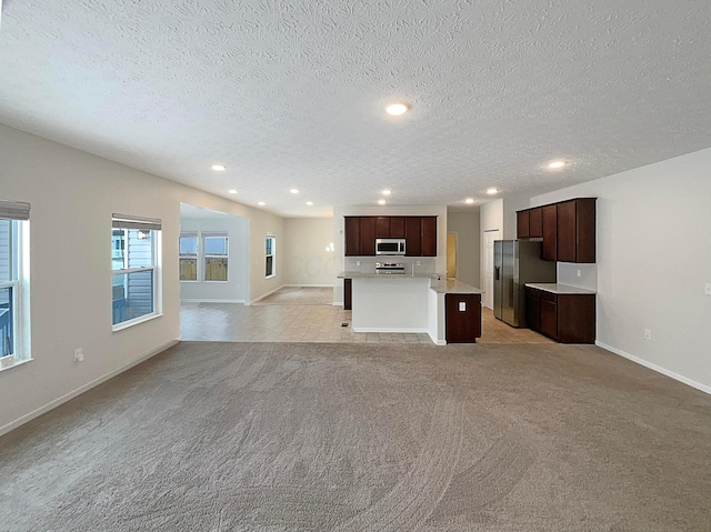 unfurnished living room featuring recessed lighting, baseboards, a textured ceiling, and light colored carpet