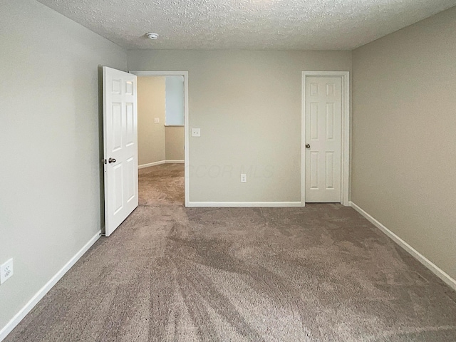 unfurnished bedroom featuring carpet, a textured ceiling, and baseboards