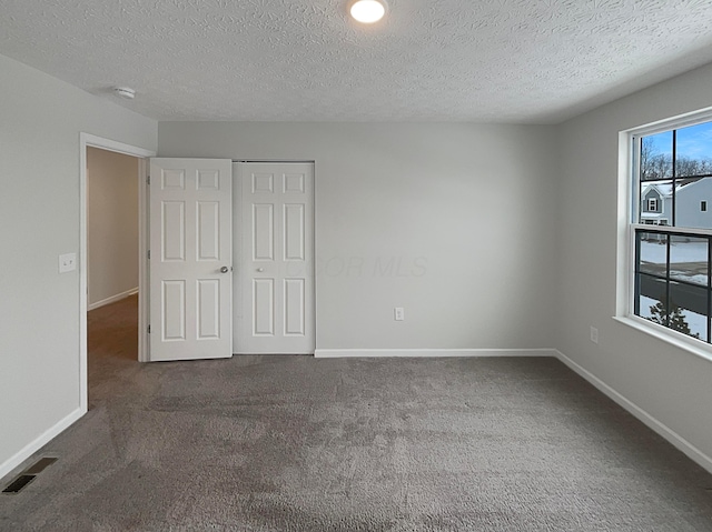 unfurnished bedroom featuring dark colored carpet, visible vents, and baseboards