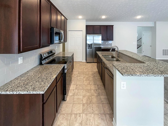 1128 Legacy Ln, Pataskala, OH 43062 - kitchen with stainless steel appliances, dark brown cabinetry, a textured ceiling, decorative backsplash, and stone countertops
