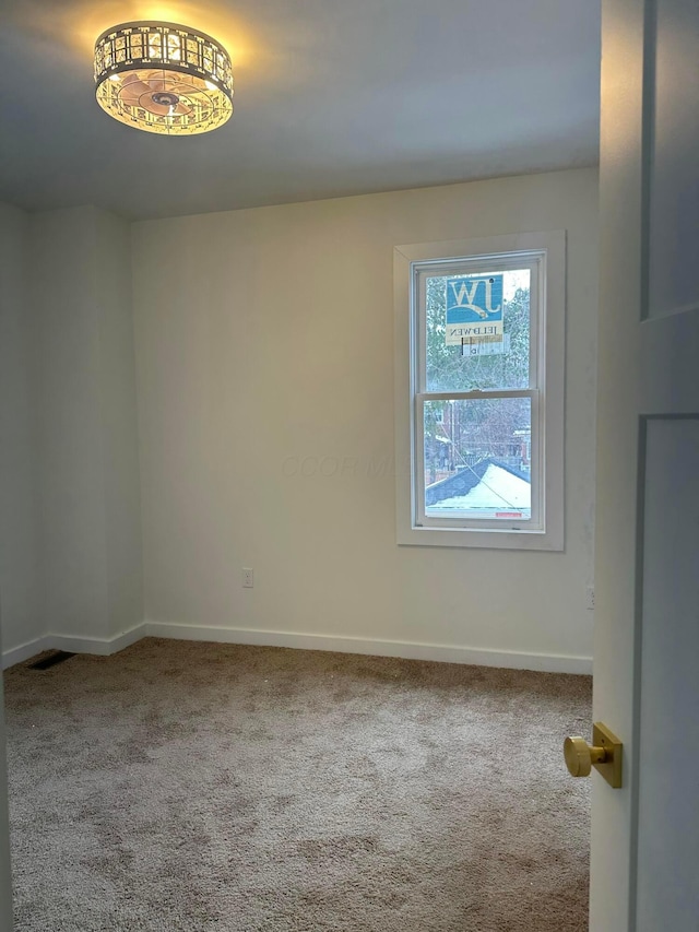 spare room featuring carpet floors and baseboards