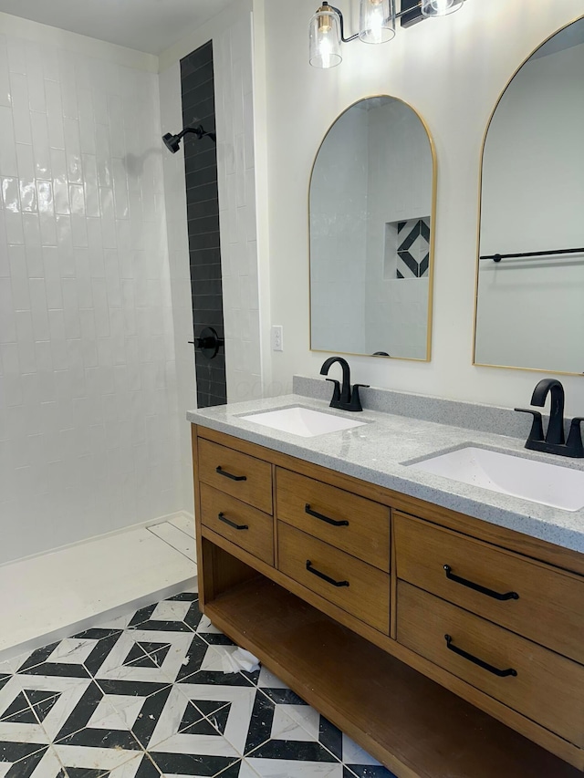 full bathroom with a sink, a tile shower, and double vanity