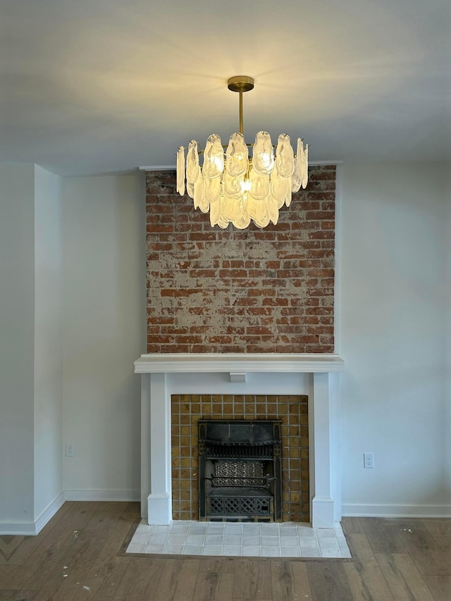 details with a chandelier, baseboards, a tiled fireplace, and wood finished floors