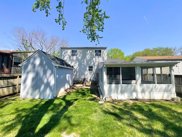 back of house with a storage unit, a yard, an outbuilding, and a sunroom