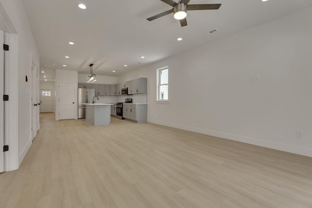 unfurnished living room featuring recessed lighting, visible vents, light wood-style flooring, ceiling fan, and baseboards