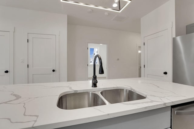 kitchen featuring a sink, visible vents, stainless steel dishwasher, fridge, and light stone countertops