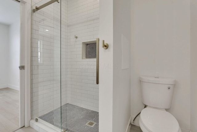 bathroom with a stall shower, baseboards, and toilet