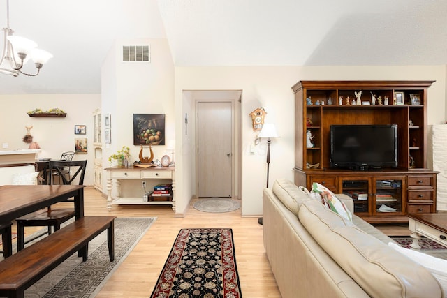 living room with light wood finished floors, visible vents, and a notable chandelier