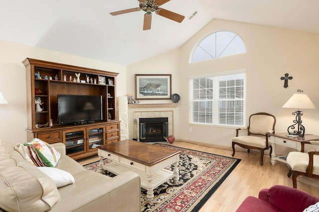 living area featuring visible vents, a tiled fireplace, ceiling fan, wood finished floors, and high vaulted ceiling