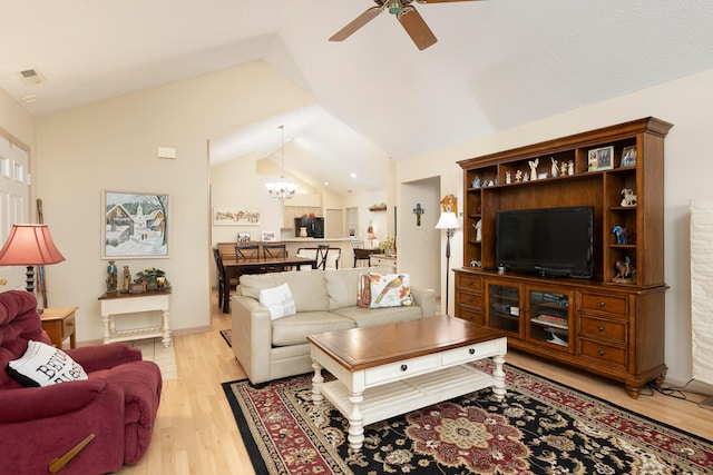 living room featuring light wood-type flooring, lofted ceiling, visible vents, and ceiling fan with notable chandelier