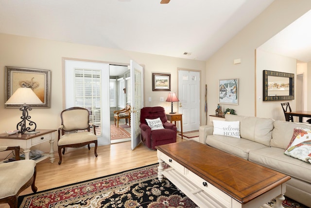 living area with visible vents, vaulted ceiling, and wood finished floors